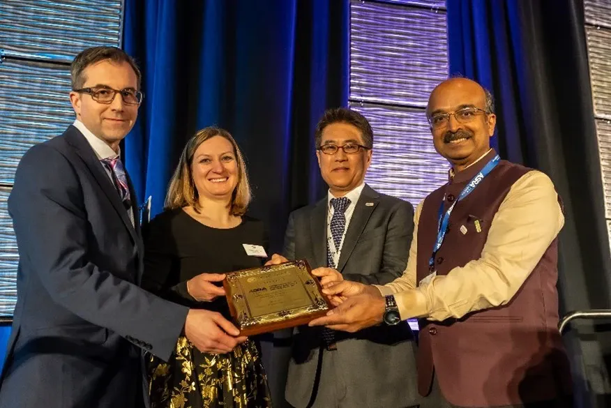 Dr. David Provenzano and three colleagues holding a plaque on stage