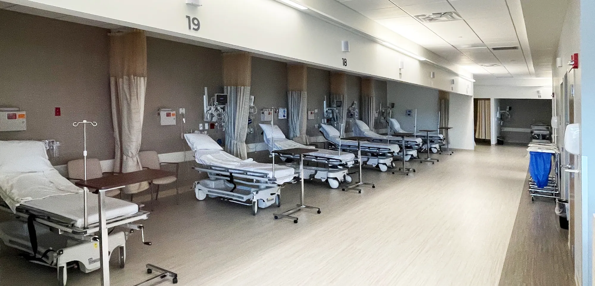 A row of patient stretchers in a bright recovery area